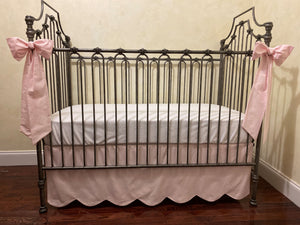 Scalloped edge crib skirt and two accent bows in pale pink fabric