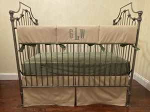 Metal crib with beige and green bedding in a room setting