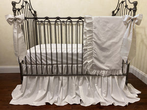 Vintage-style crib with white bedding and decorative ribbons in a room.