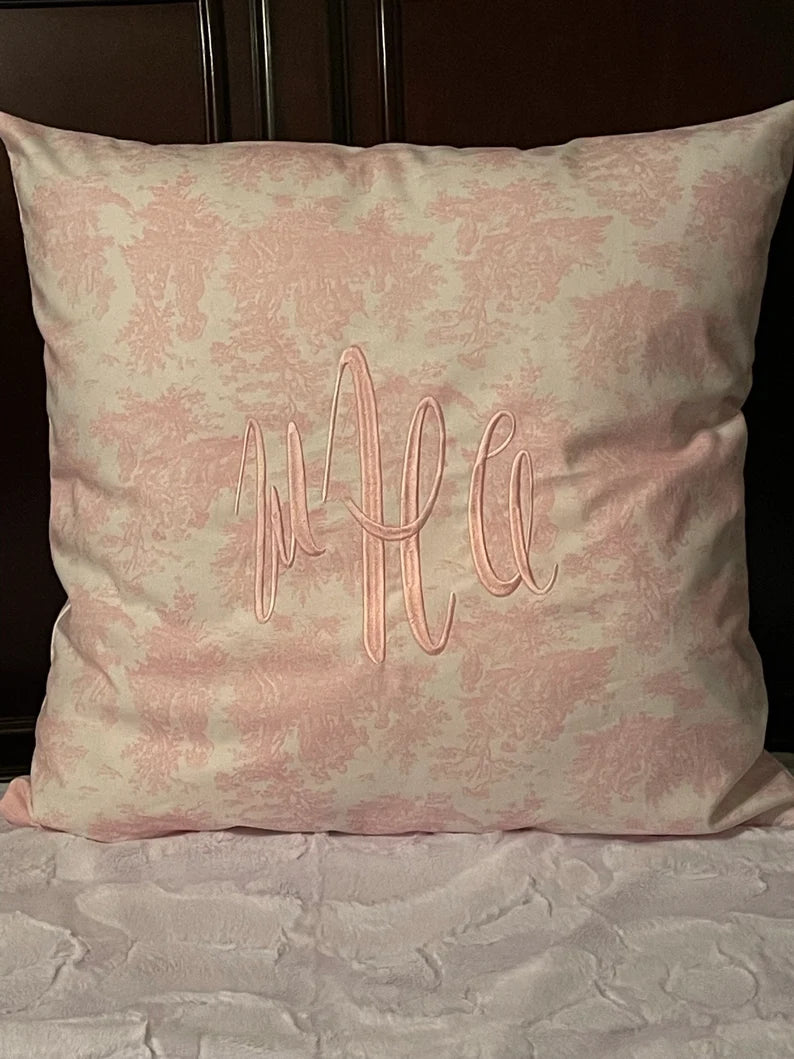 Decorative pillow with monogram embroidery on a pink toile background